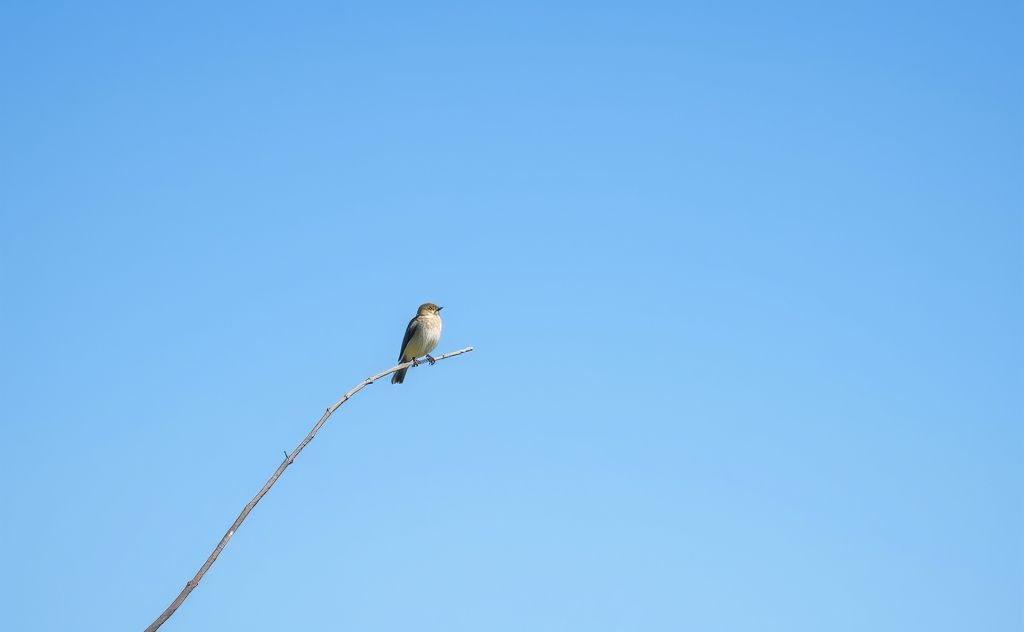 A bird resting on a branch under a clear blue sky.