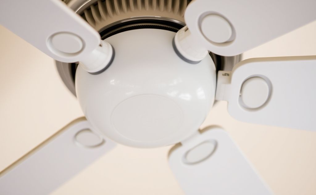 A close-up of a ceiling fan with a wrench and screws nearby.