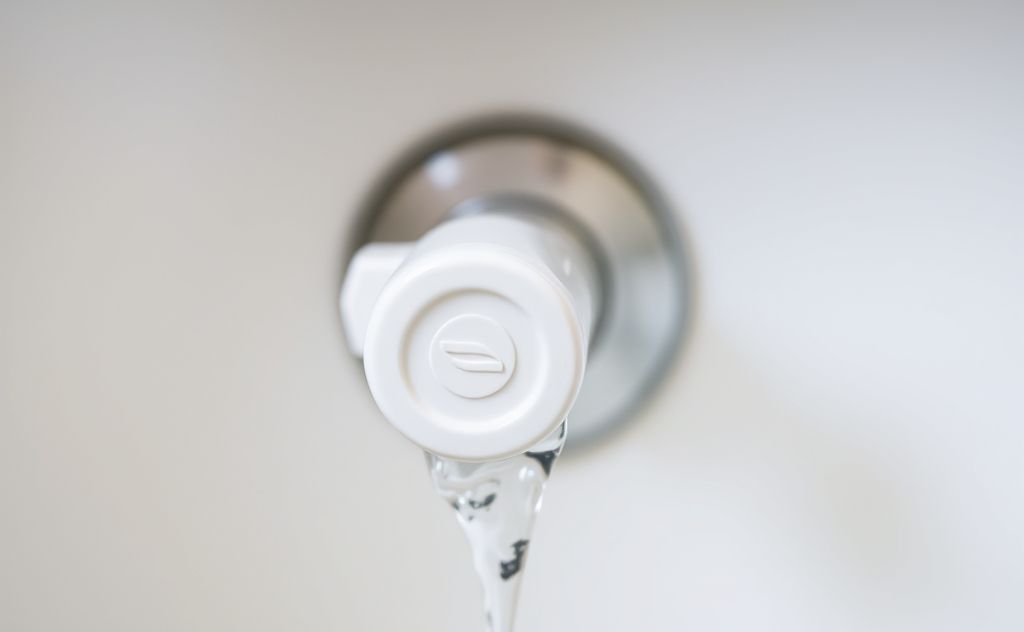 A close-up of a toilet fill valve with water flowing.