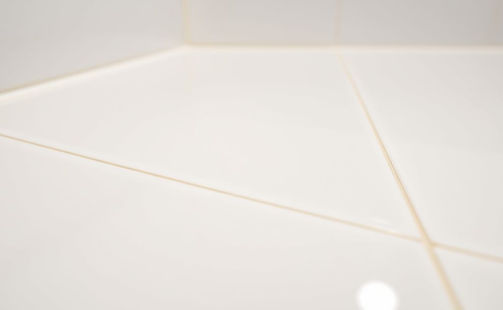 A close-up of sparkling clean bathroom tiles and grout lines.