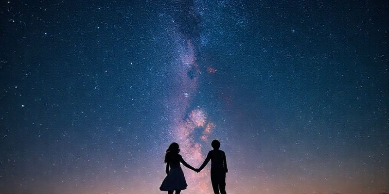 A couple holding hands under a starry sky, representing astrological love compatibility