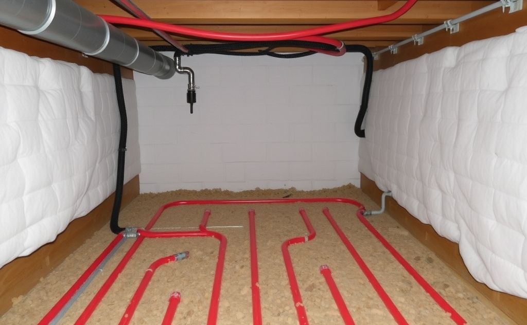 A radiant heating system warming a crawl space with pipes and insulation.