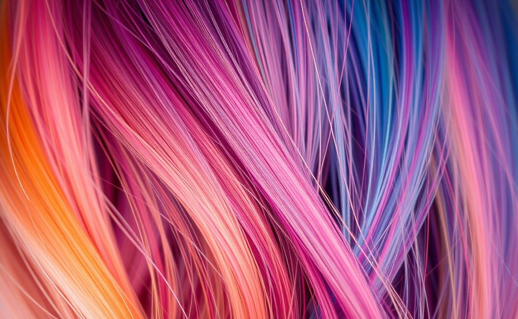 A close-up of vibrant hair strands with a heat protectant spray.