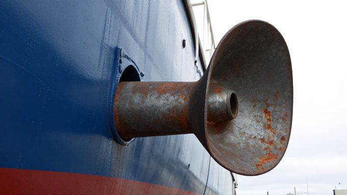 Severely corroded boat propeller with an intact, unpainted sacrificial anode nearby, highlighting the anode's protective function.